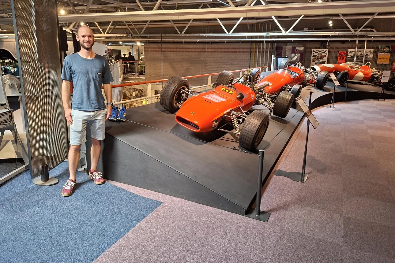 Thijs van den Berg naast een oranje DAF-formulewagen in het DAF Museum